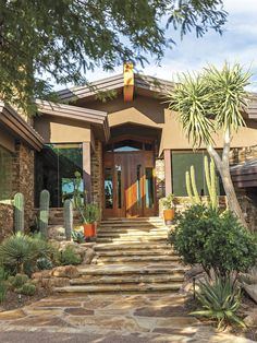 a house with steps leading up to the front door and cactus in pots on either side