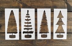 four different types of trees cut out from paper on a wooden table with wood planks