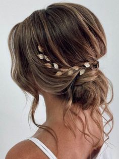 a woman with her hair in a low bun and two gold leaves on the side