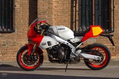 a red and white motorcycle parked in front of a brick building