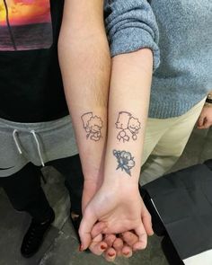 two people holding hands with tattoos on them