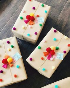 three wrapped presents with pom - poms on them sitting on a wooden floor