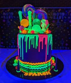 a multicolored cake with candy on top and icing dripping down the side