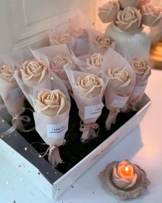 a bunch of roses sitting in a box next to a candle