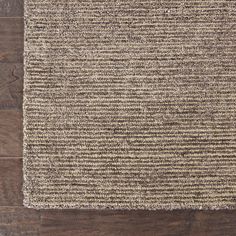 a brown and beige area rug on top of a wooden floor next to a wall