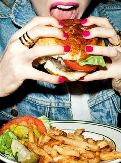 a woman eating a hamburger and french fries