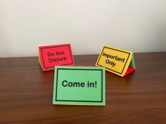 three colorful sticky notes sitting on top of a wooden table next to each other with the words do not disturb and important only