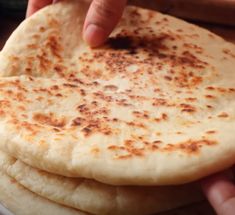 a stack of flat bread on a plate being held by a person's hand