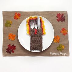 a white plate topped with a crocheted turkey fork holder