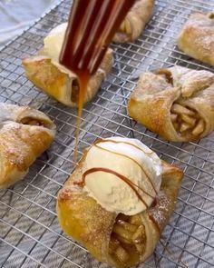 several pastries on a cooling rack with ice cream being drizzled onto them