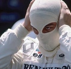 a man with a white mask covering his face and holding his hands to his ears