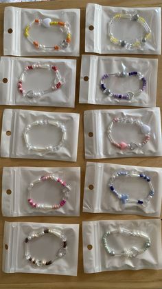 eight bracelets in plastic bags lined up on a wooden table with white tags attached to them