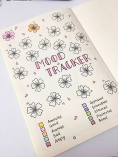 an open notebook with flowers on it and the words mood tracker written in different colors