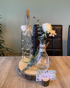 two vases filled with flowers on top of a wooden table next to a bottle