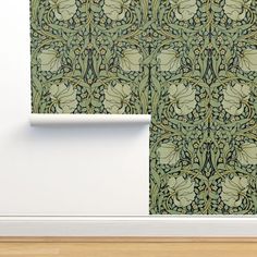 an ornate wallpaper design with green leaves and flowers on a white wall next to a wooden floor