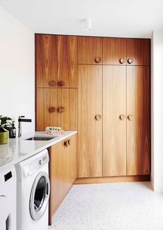 a washer and dryer in a small room with wooden cupboards on the wall