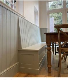 a wooden bench sitting next to a window in a room with white walls and wood flooring