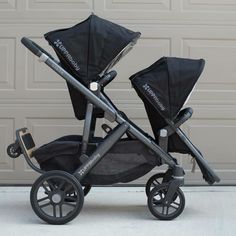 two baby strollers sitting side by side in front of a garage door