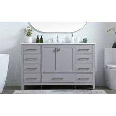 a white toilet sitting next to a gray vanity with two sinks and a round mirror