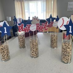 baseball themed centerpieces in glass vases on a table with snacks and decorations