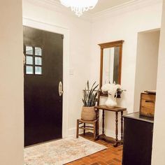 an entryway with a mirror, chair and table in front of the door that leads to another room