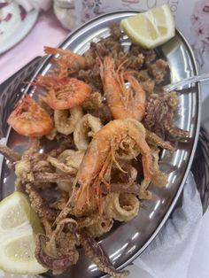 a plate with shrimp and lemon wedges on it