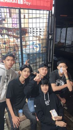 group of young men posing for the camera in front of a caged area with food