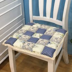 a white chair with blue and white pillows on it