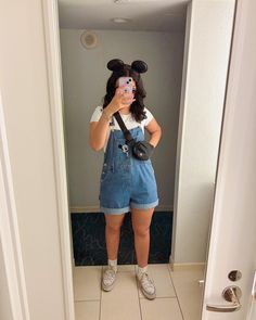 a woman taking a selfie in the bathroom with mickey mouse ears on her head