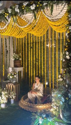 a man sitting in front of a stage decorated with yellow flowers