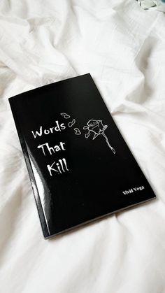 a black book with words that kill written on it sitting on top of a bed