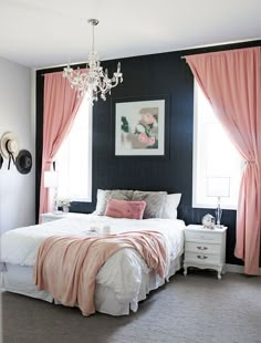 a bedroom with black walls, pink curtains and a white bed in front of a chandelier