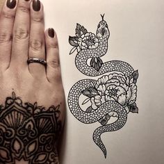 a woman's hand with a tattoo on it next to a drawing of a snake