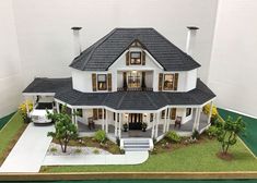 a model house with a car parked in front of it on a green floored area