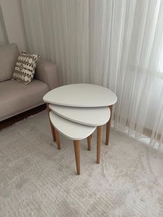 three white tables sitting in front of a couch