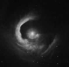 a black and white photo of a spiral shaped object in the sky with stars around it