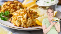 a woman holding a plate full of food with lemons and other foods on it