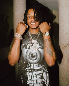 a young man with dreadlocks and tattoos on his arm posing for the camera