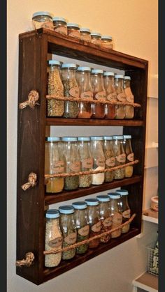 a shelf filled with lots of different types of spices on top of wooden shelves next to a wall