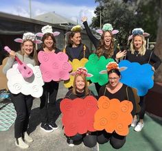 a group of women standing next to each other holding up paper cut out sheeps