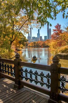 there is a boat on the water in the lake with trees around it and skyscrapers in the background