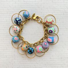 Colorful floral polymer beads and gold ring charm bracelet to add the perfect finishing touch to any outfit. 8"L with lobster clasp. Beads are securely wire-wrapped to perfect on our signature brass-plated cable chain with Lenora Dame hang tag. Bohemian Gold Beaded Bracelet With Flower Charm, Polymer Beads, Bead Charm Bracelet, Hang Tags, Last Minute Gifts, Cable Chain, Arm Band, Bead Charms, Wire Wrapped