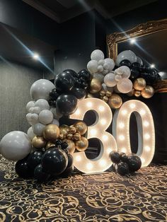 the balloon arch is decorated with black, white and gold balloons that spell out the number thirty