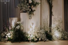 an arrangement of white flowers and greenery on display at a wedding reception in front of curtains