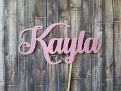 a cake topper with the word kaja on it sitting on a wooden table