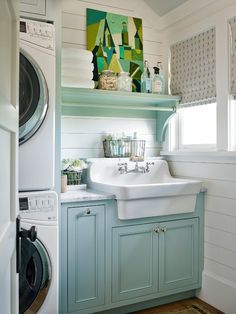 a washer and dryer in a room with white walls, wood floors and blue cabinets