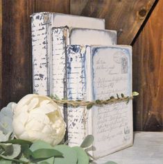 an old book with some flowers on top of it next to a wooden wall and fence