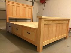 a wooden bed frame with two drawers underneath the headboard and foot board, in a garage