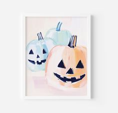 two pumpkins with faces painted on them in pastel blue, orange and pink