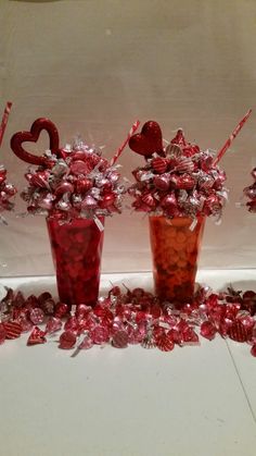 two vases filled with candy and hearts on top of a table next to each other